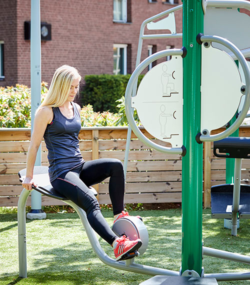 A woman is exercising outdoors at an outdoor fitness gym area in a residential space.